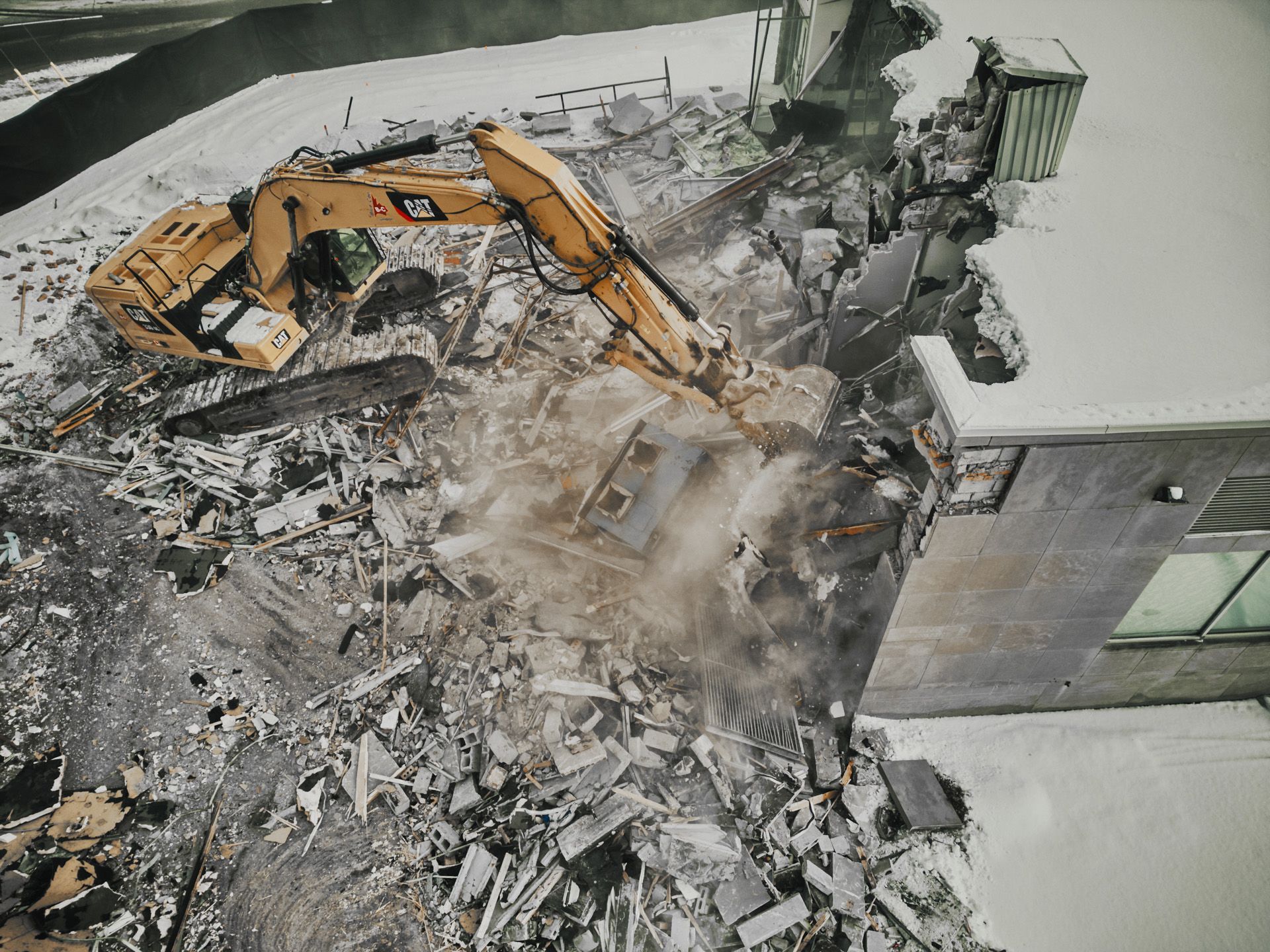 An excavator is demolishing a building with a lot of rubble.