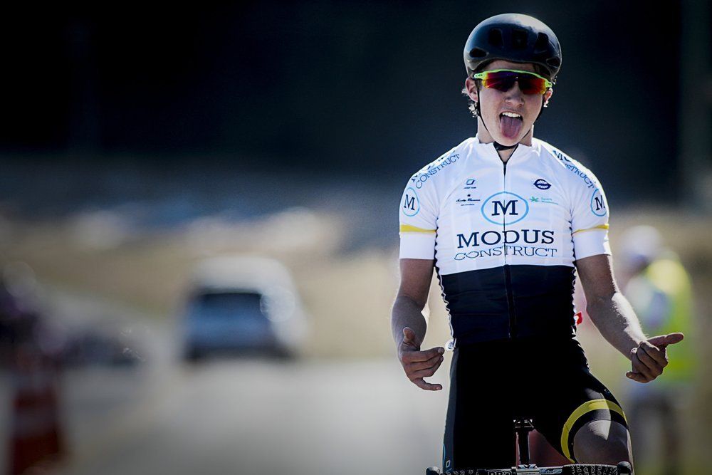 A man wearing a helmet and sunglasses is riding a bike on a road.