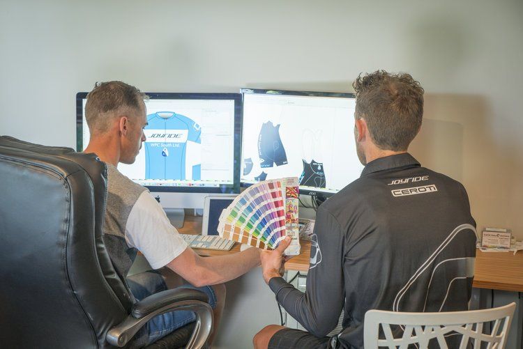 Two men are sitting in front of a computer looking at a color chart.