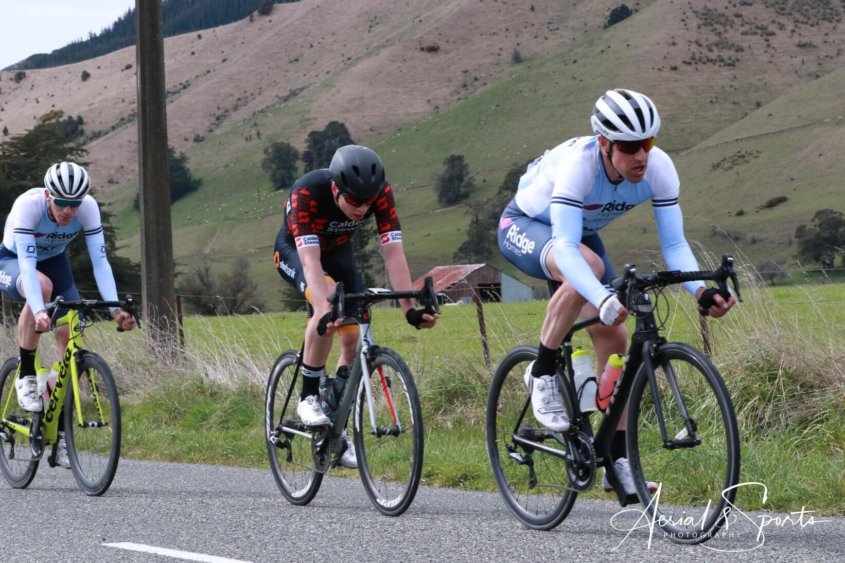 Three men are riding bicycles down a road.