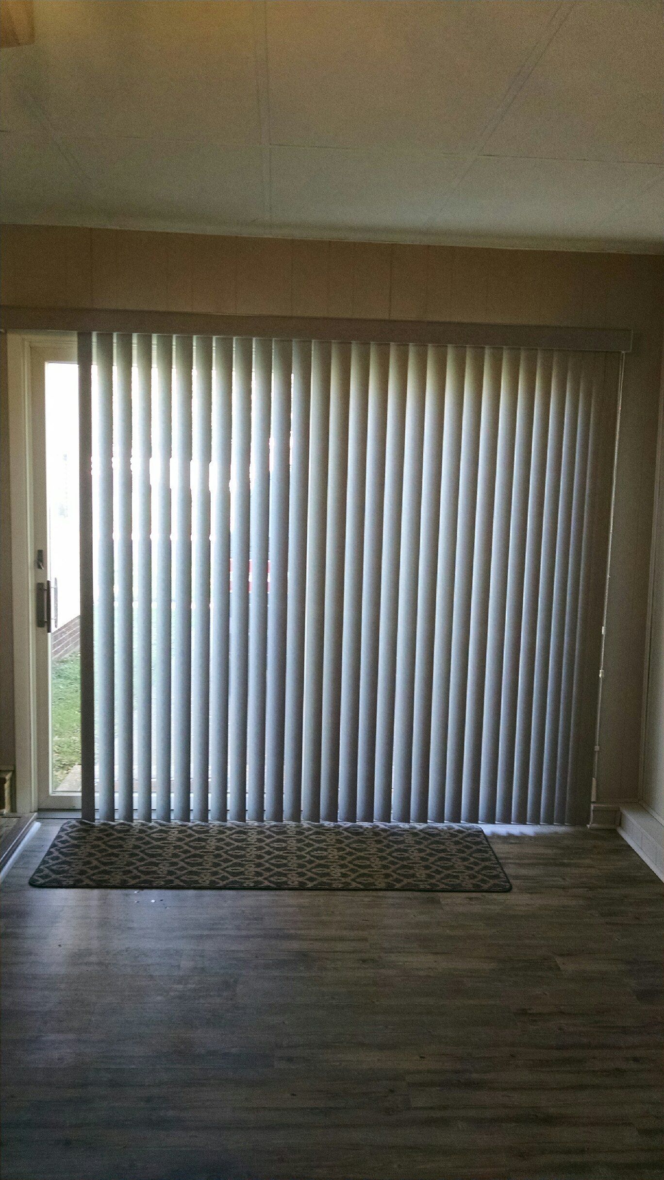 An empty room with a sliding glass door and vertical blinds. — East Peoria, IL — Blinds For Less