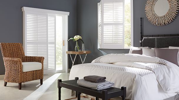 A bedroom with a bed , chair , bench and mirror.