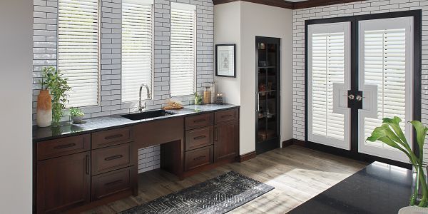 A bathroom with a sink , cabinets , and shutters.