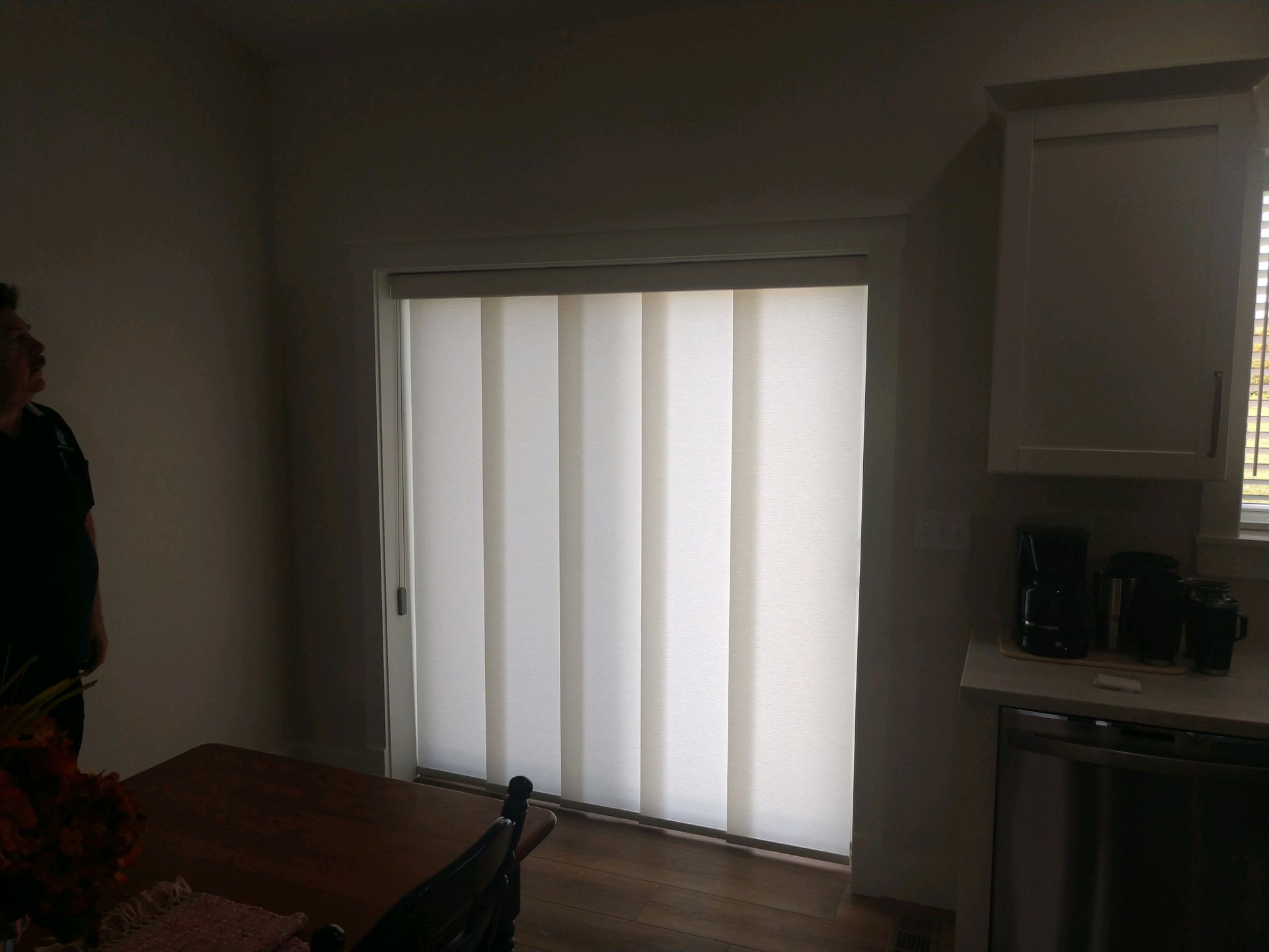 A man is standing in front of a sliding glass door with vertical blinds  — East Peoria, IL — Blinds For Less