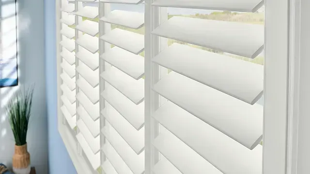 A close up of a window with white shutters in a living room.