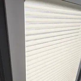 A close up of a white roller shutter on a window.