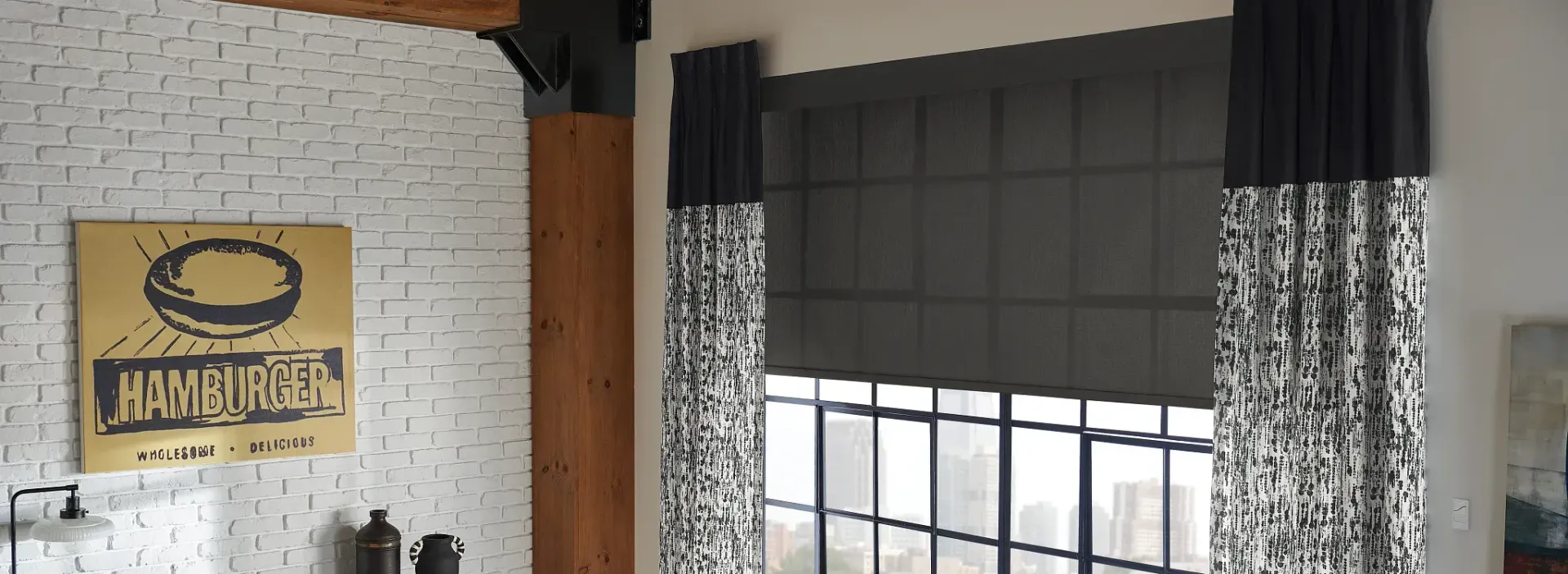 A living room with a brick wall and black and white curtains.