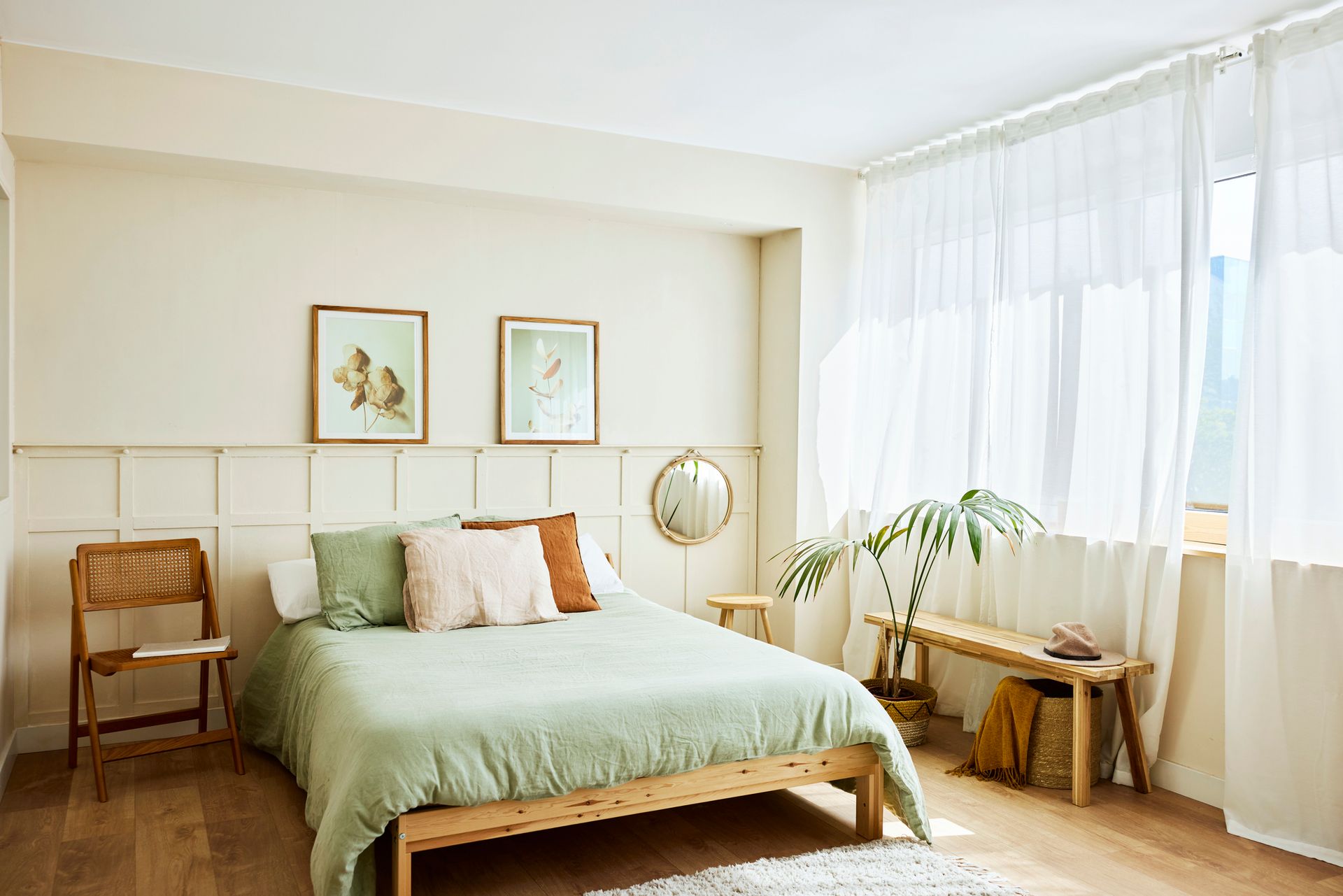 A bedroom with a bed , chair , bench and window.