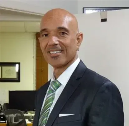 A bald man in a suit and tie is smiling for the camera.