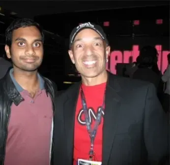 Two men are posing for a picture with one wearing a red shirt that says cnn