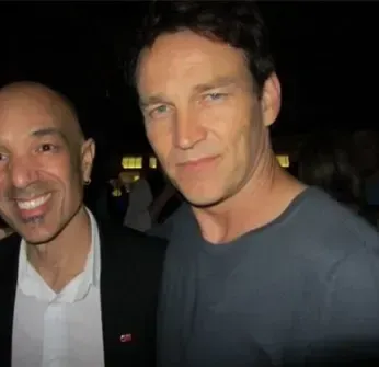 Two men are posing for a picture and smiling for the camera