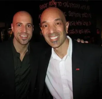 Two bald men are posing for a picture in front of a sign that says