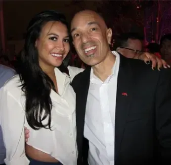 A man in a suit and a woman in a white shirt pose for a picture