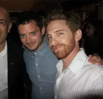 Three men are posing for a picture together and one of them has a beard.
