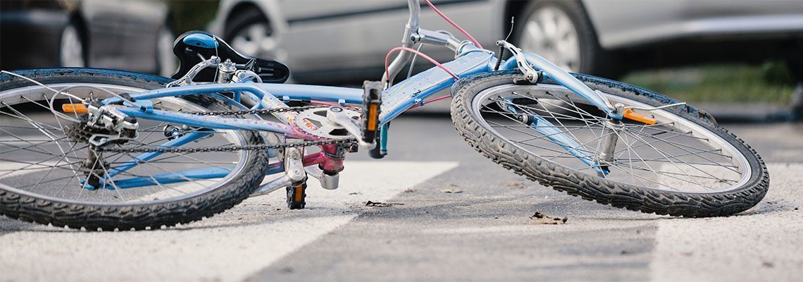 A bicycle is laying on the ground on the side of the road.
