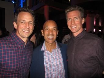 Three men are posing for a picture together in a dark room.