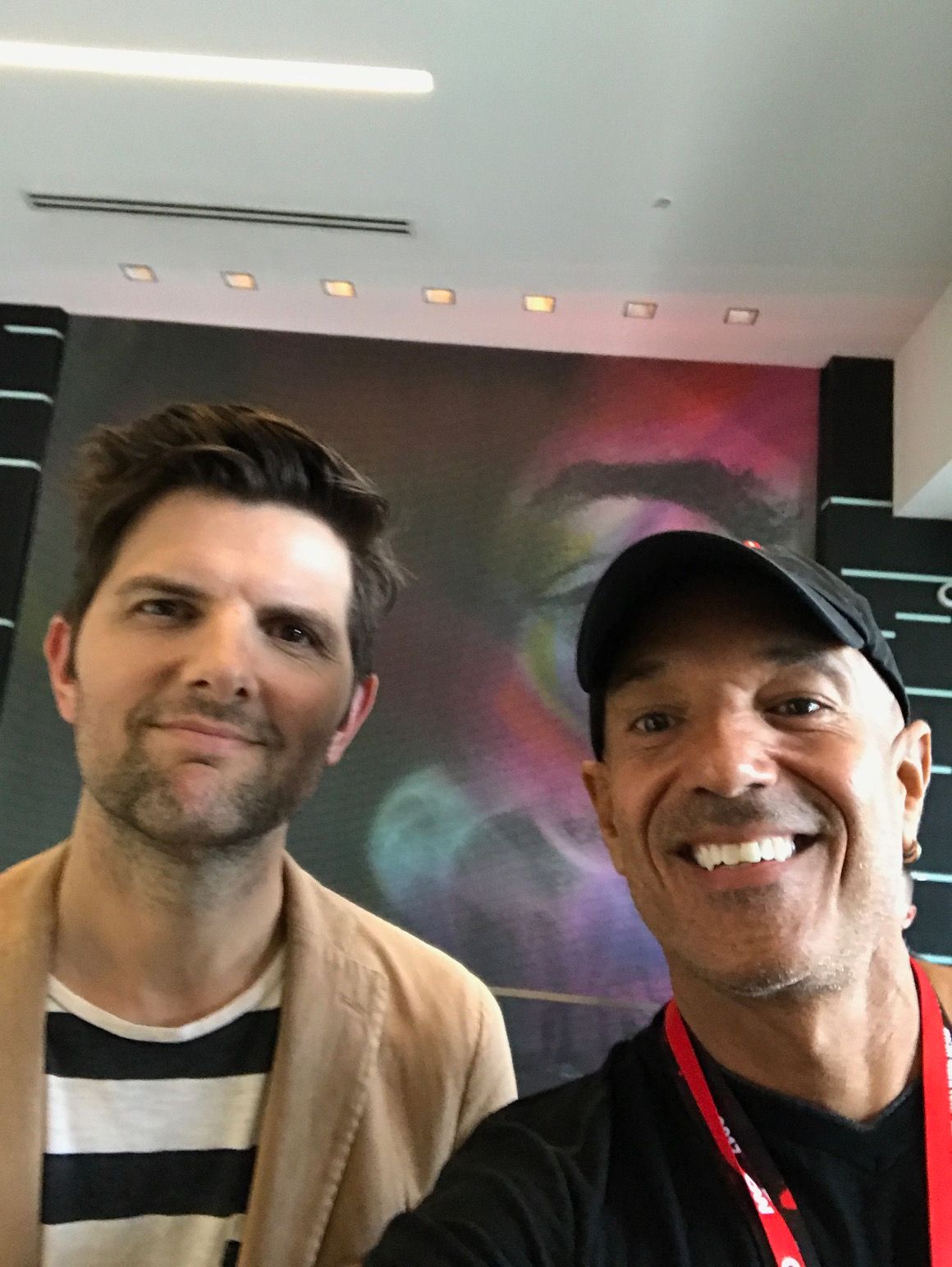 Two men are posing for a picture in front of a painting.
