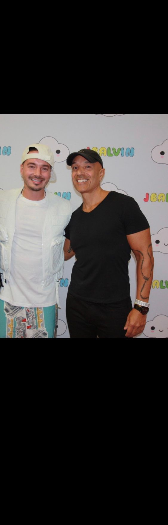 Two men are posing for a picture together in front of a wall.