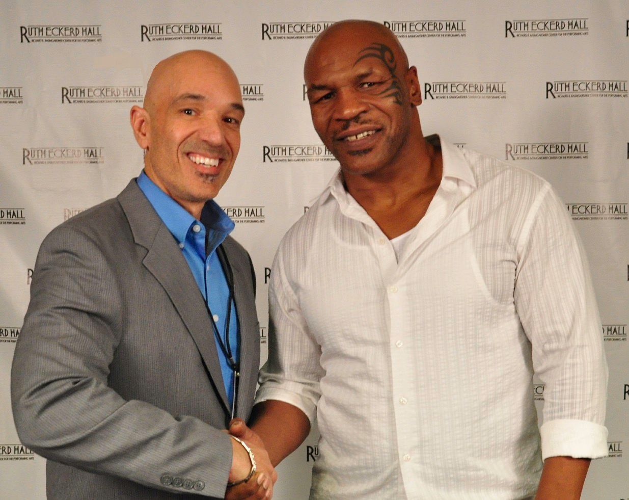 Mike tyson shakes hands with a man in a suit