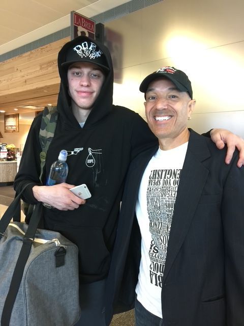 Two men are posing for a picture with one wearing a hoodie