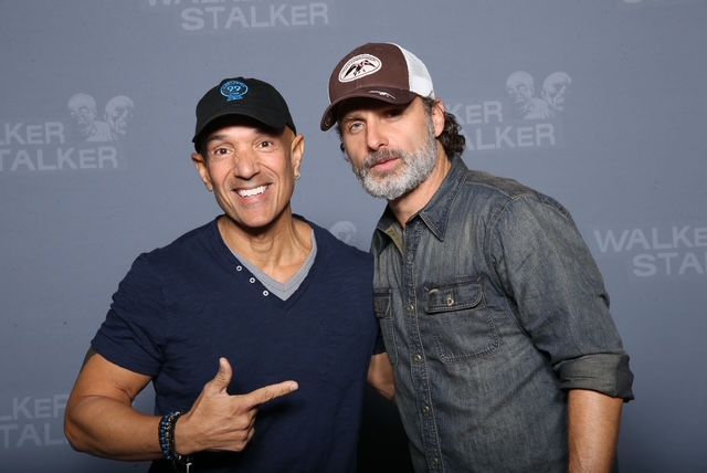 Two men are posing for a picture and one is pointing at the camera.