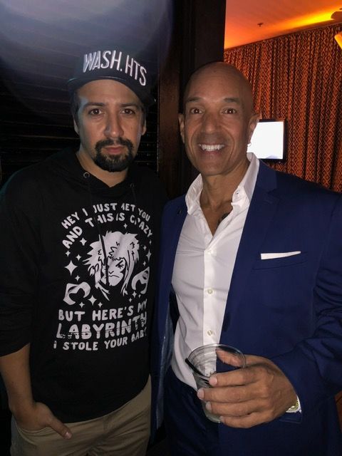 Two men posing for a picture with one wearing a shirt that says wish hits