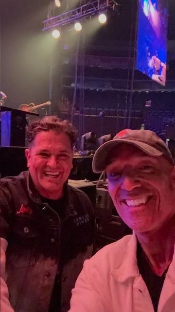 Two men are posing for a picture in front of a stage.