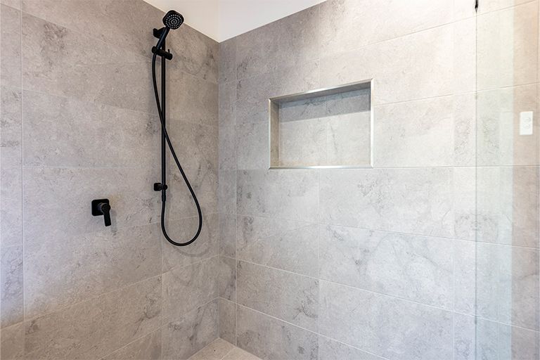 A shower with a black shower head and a glass door.