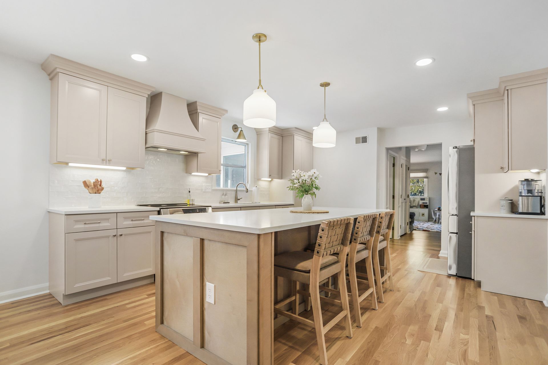 Bright modern kitchen with island, wood floors, white cabinets, and pendant lights