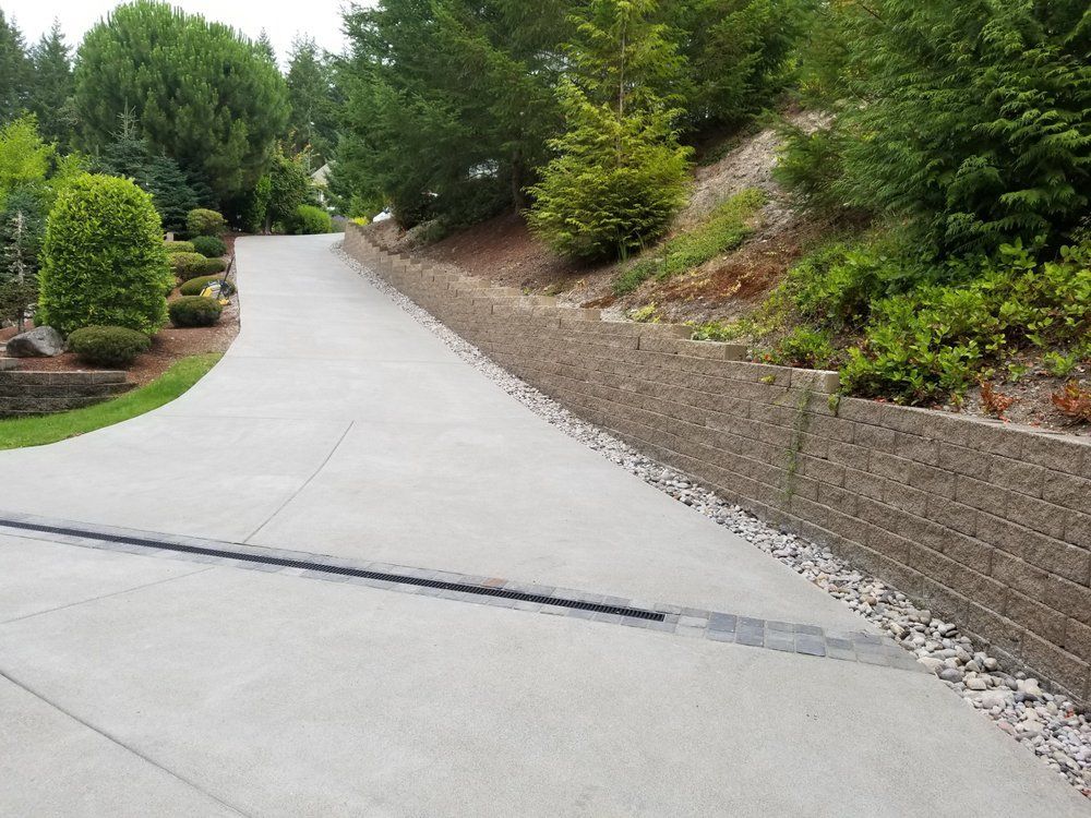 A concrete driveway with a stone wall on the side of it