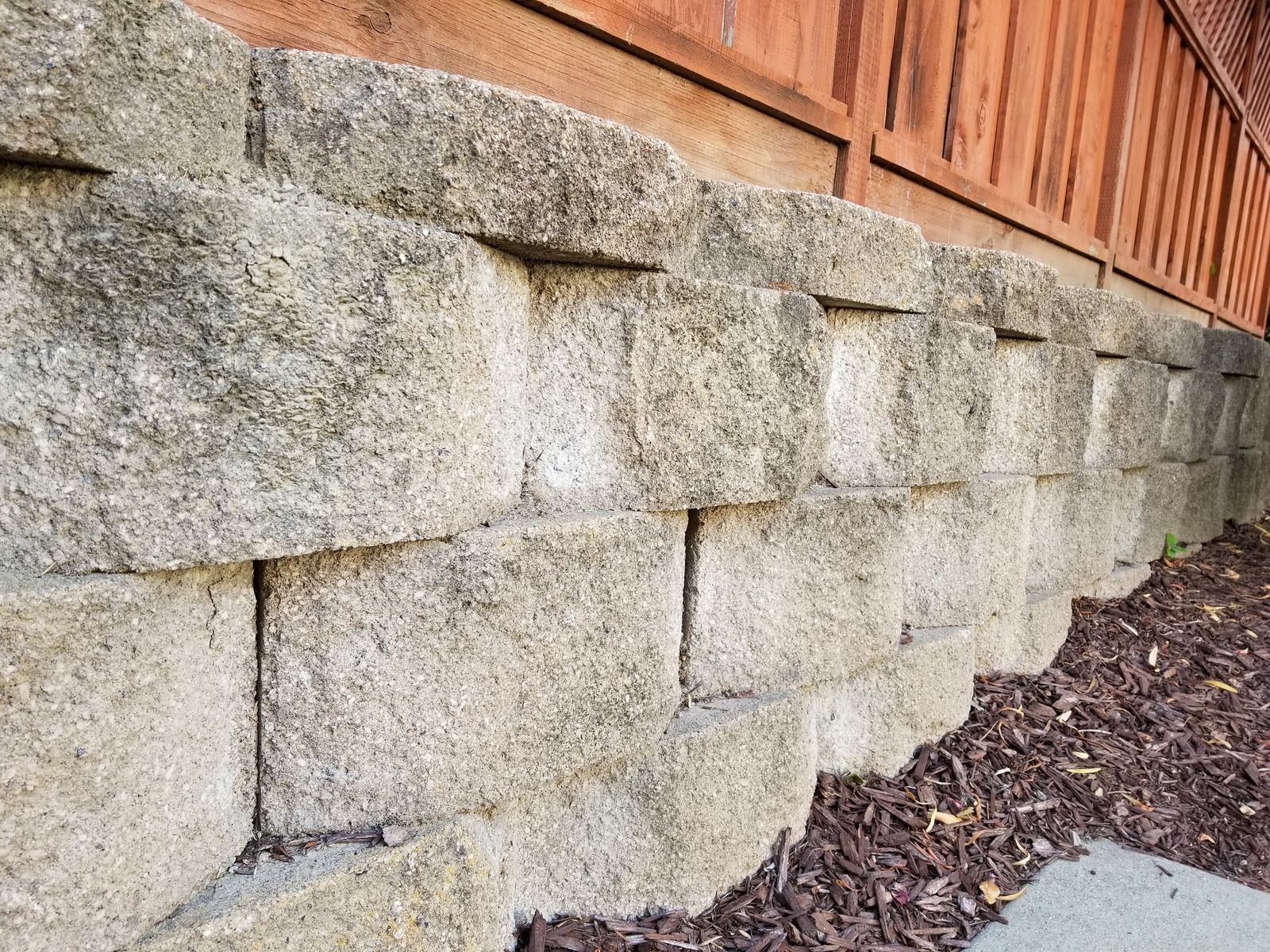 Stone retaining wall beneath a wooden fence beside a gravel path