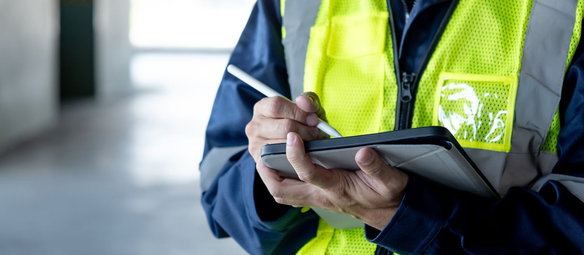 Personne portant un gilet réfléchissant prenant des notes sur une tablette.