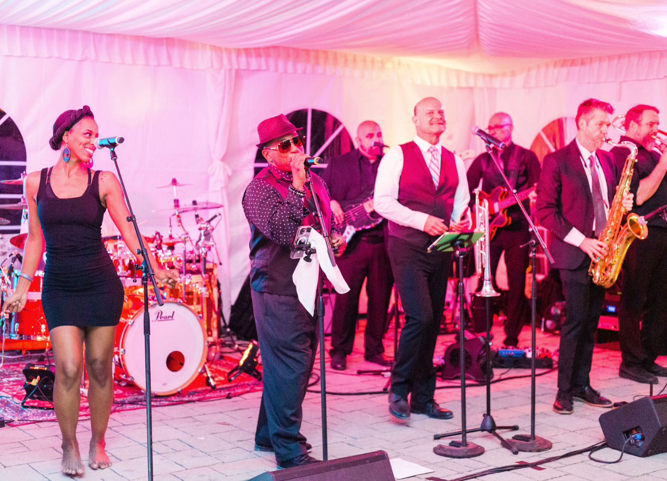 Large 10 person band playing a wedding, underneath pink soft ambient lighting.