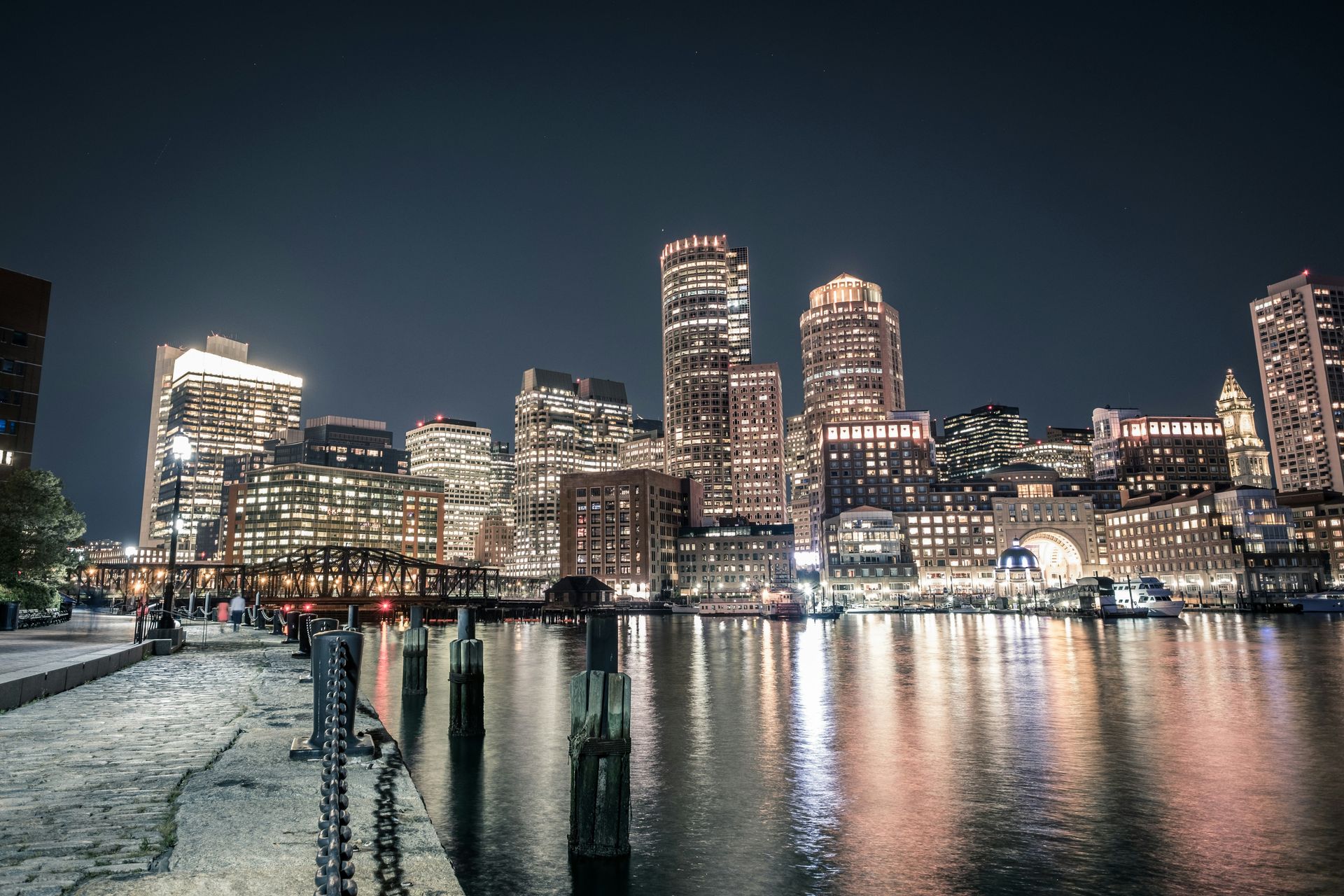Night view of Boston skyline with city lights reflecting on the water.