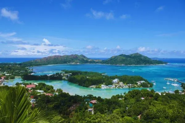 Scenic aerial view of turquoise water surrounding lush green islands under a bright blue sky.