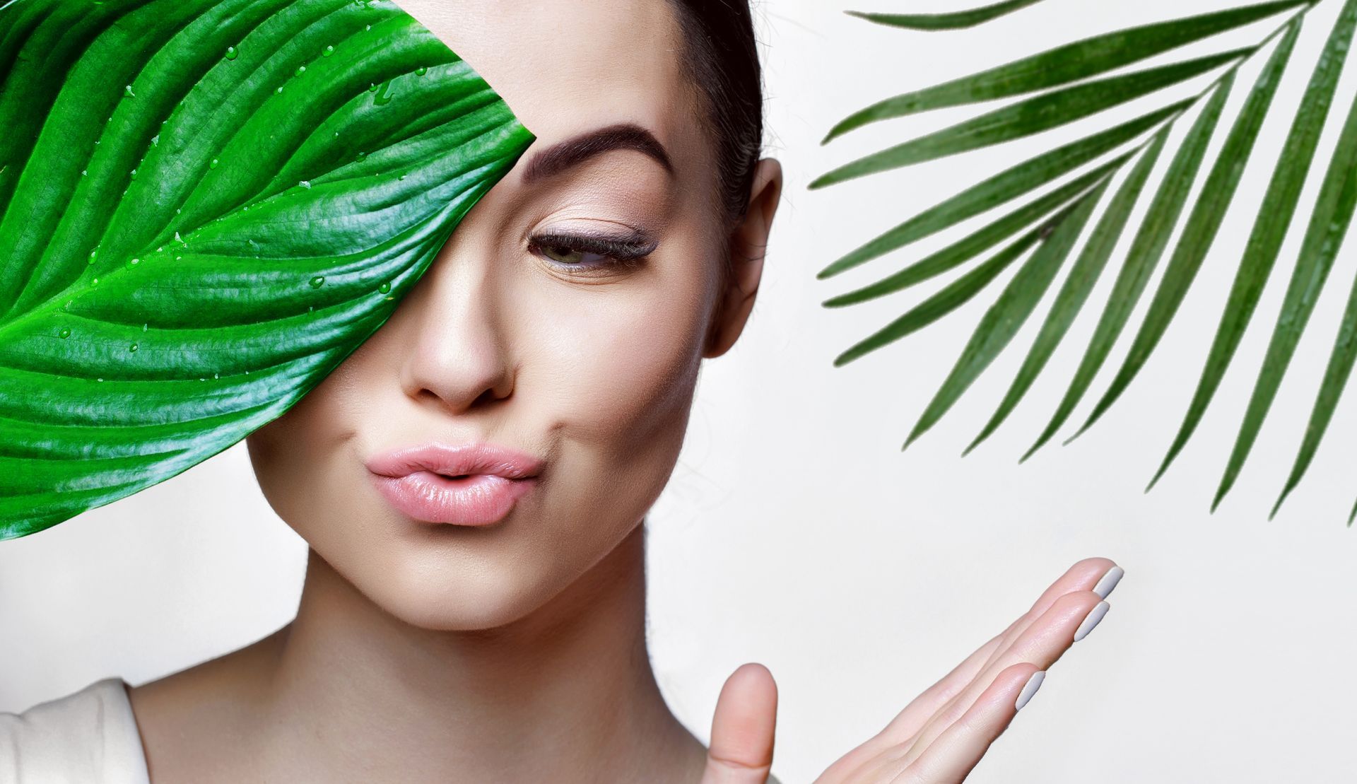 woman with clear skin next to green leaves