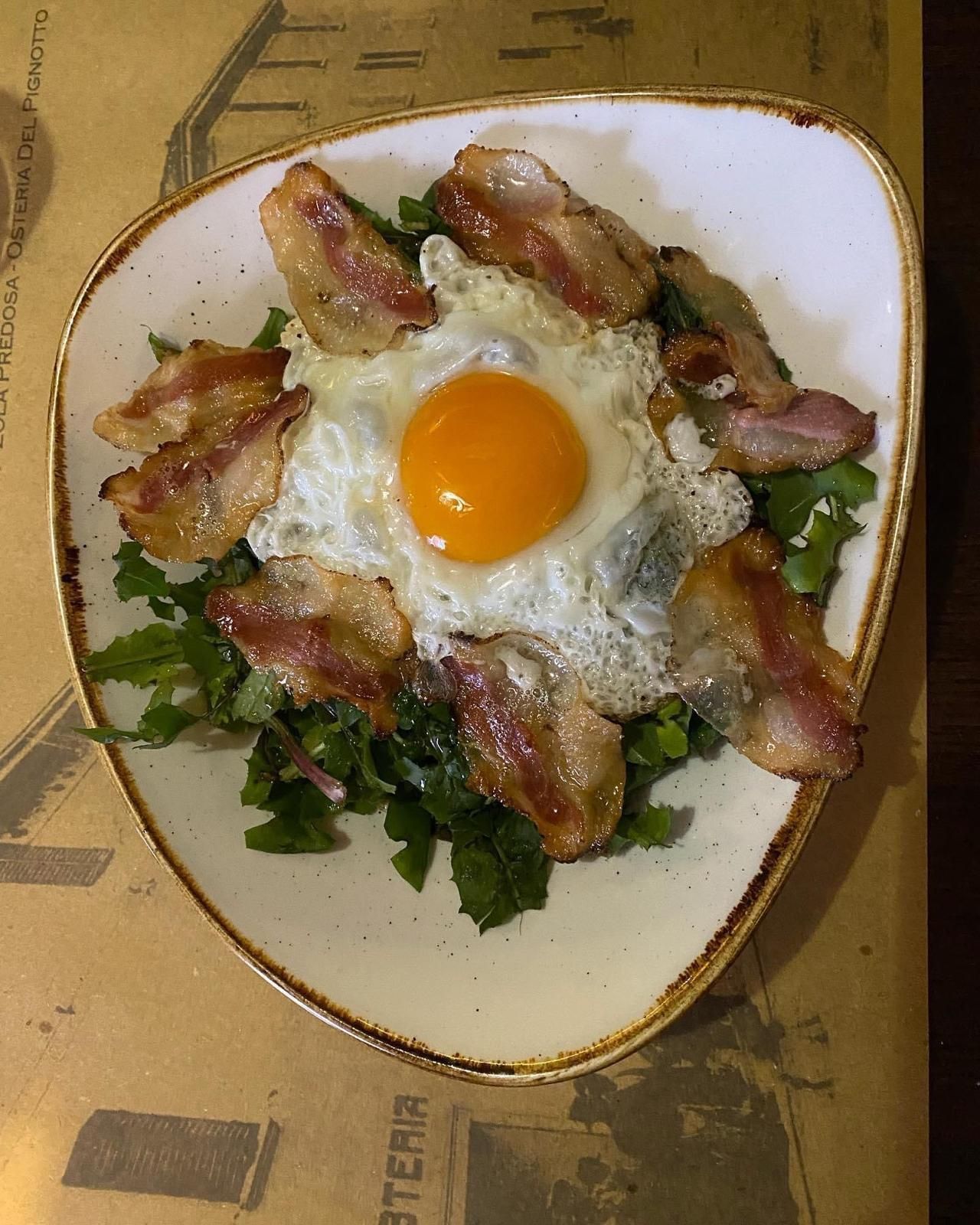 Un piatto di cibo con uova e pancetta su un tavolo