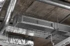 Industrial HVAC equipment and silver metallic ductwork installed on an exposed concrete ceiling.