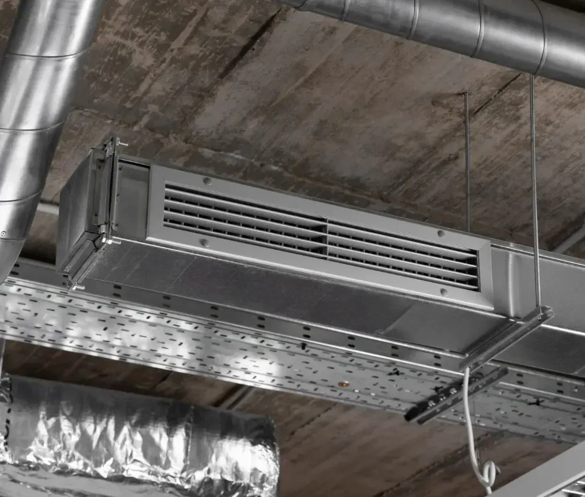 Industrial HVAC metal ventilation ducts and a vent mounted on an exposed concrete ceiling.
