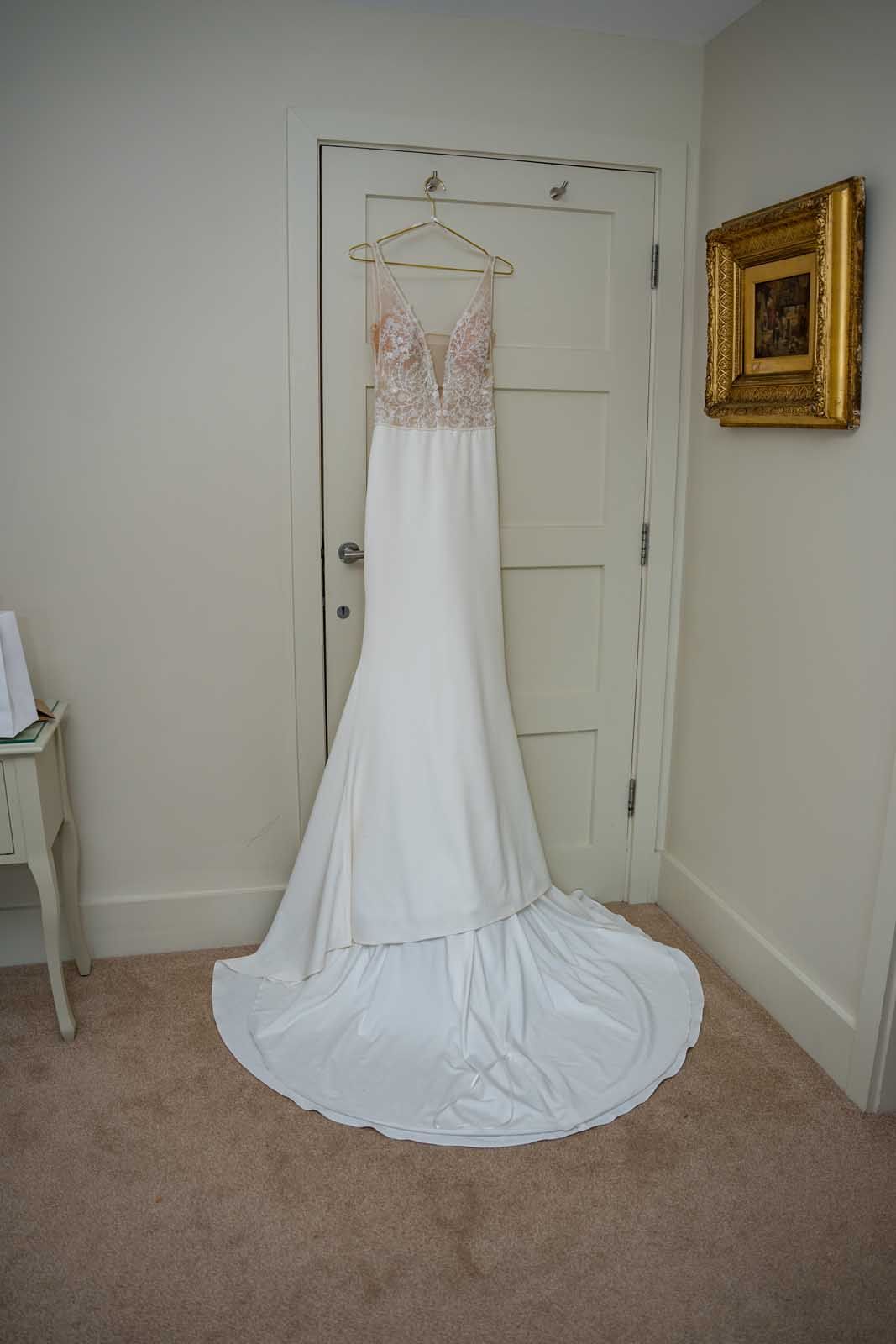 A white wedding dress is hanging on a door in a room.