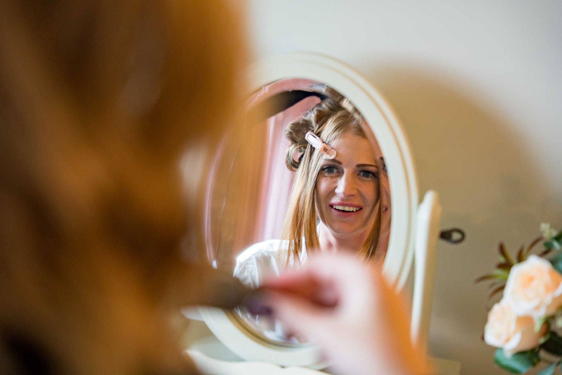 A woman is brushing her hair in front of a mirror.