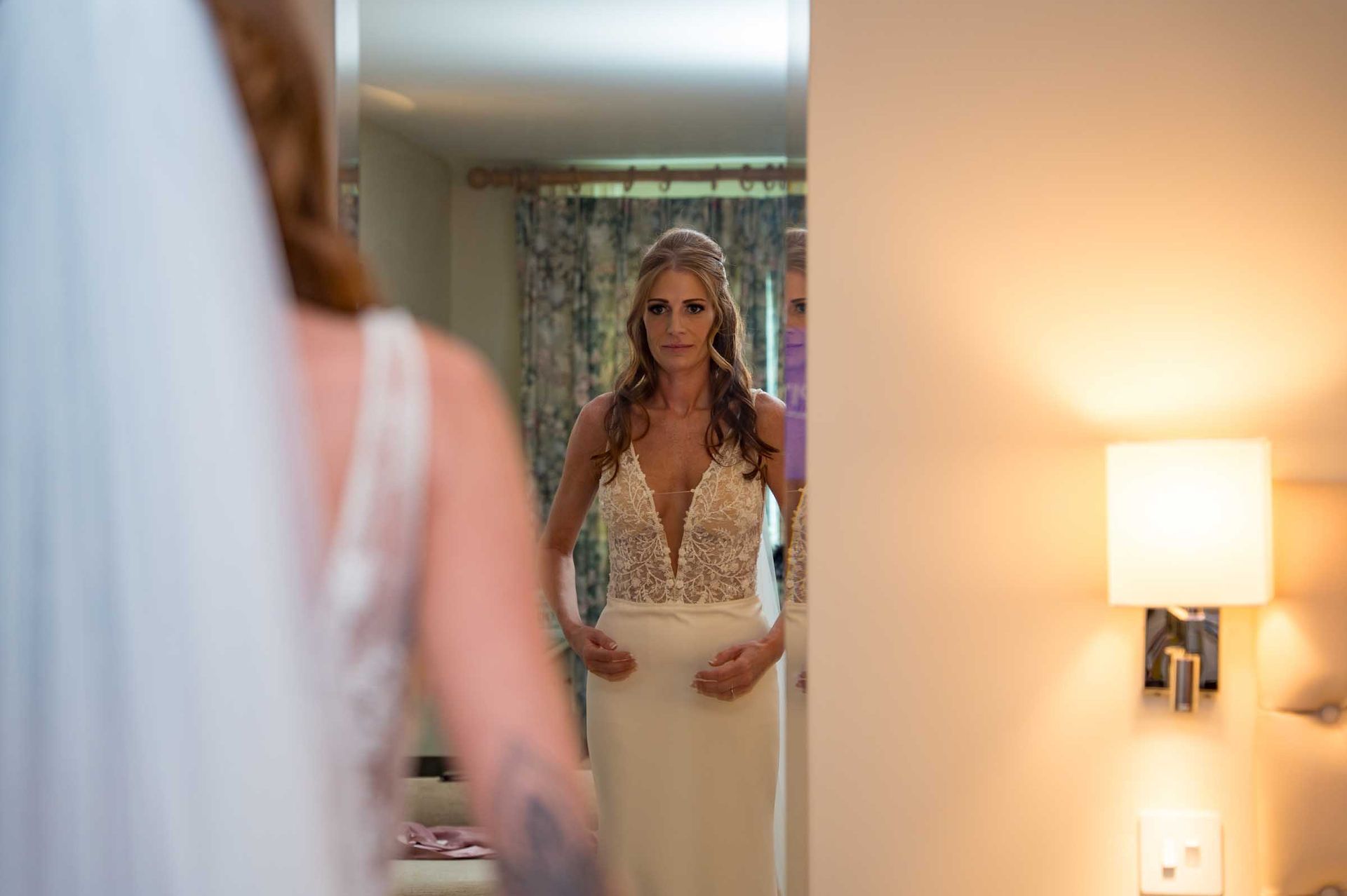 A bride is getting ready for her wedding in front of a mirror.