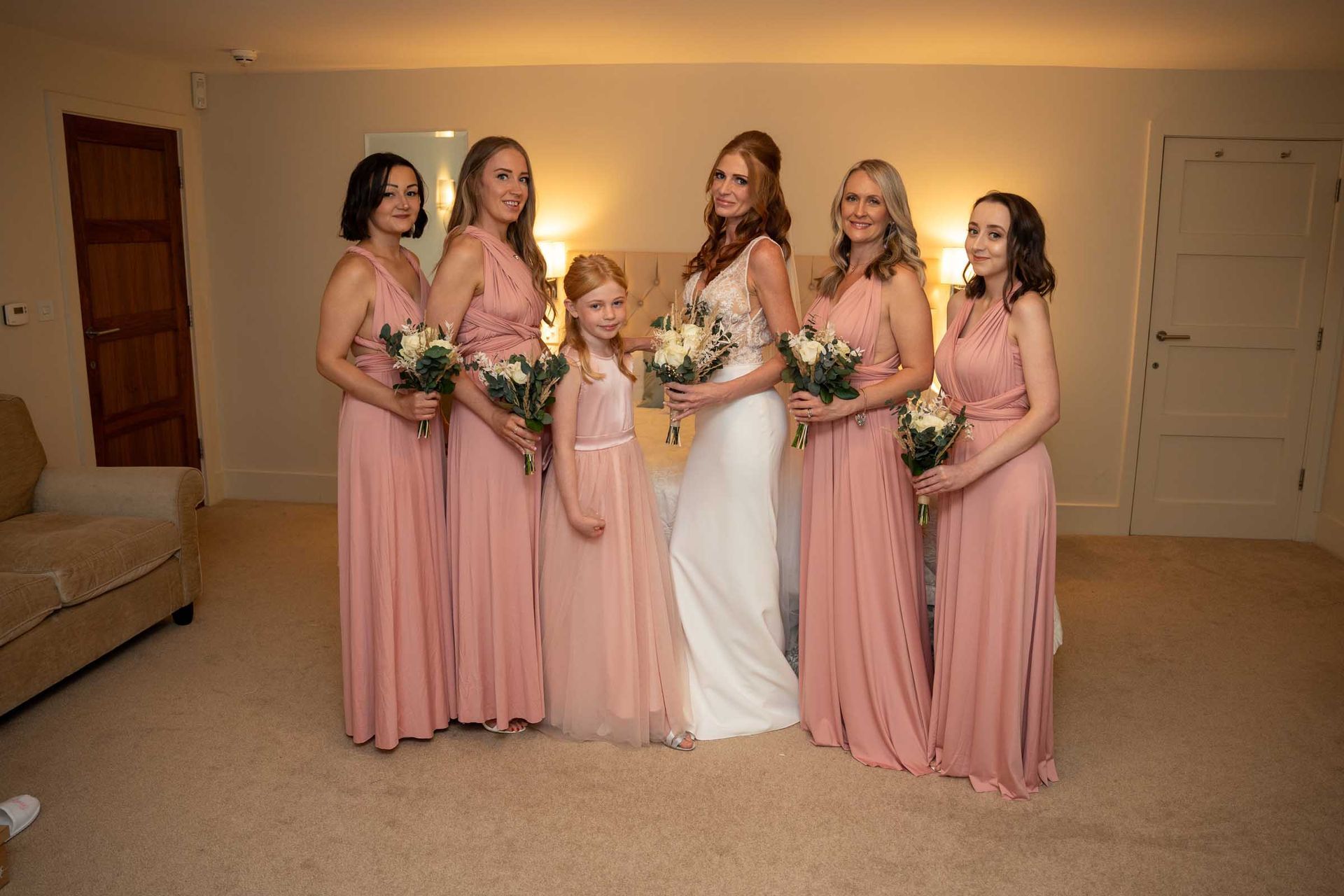 A bride and her bridesmaids are posing for a picture in a room.