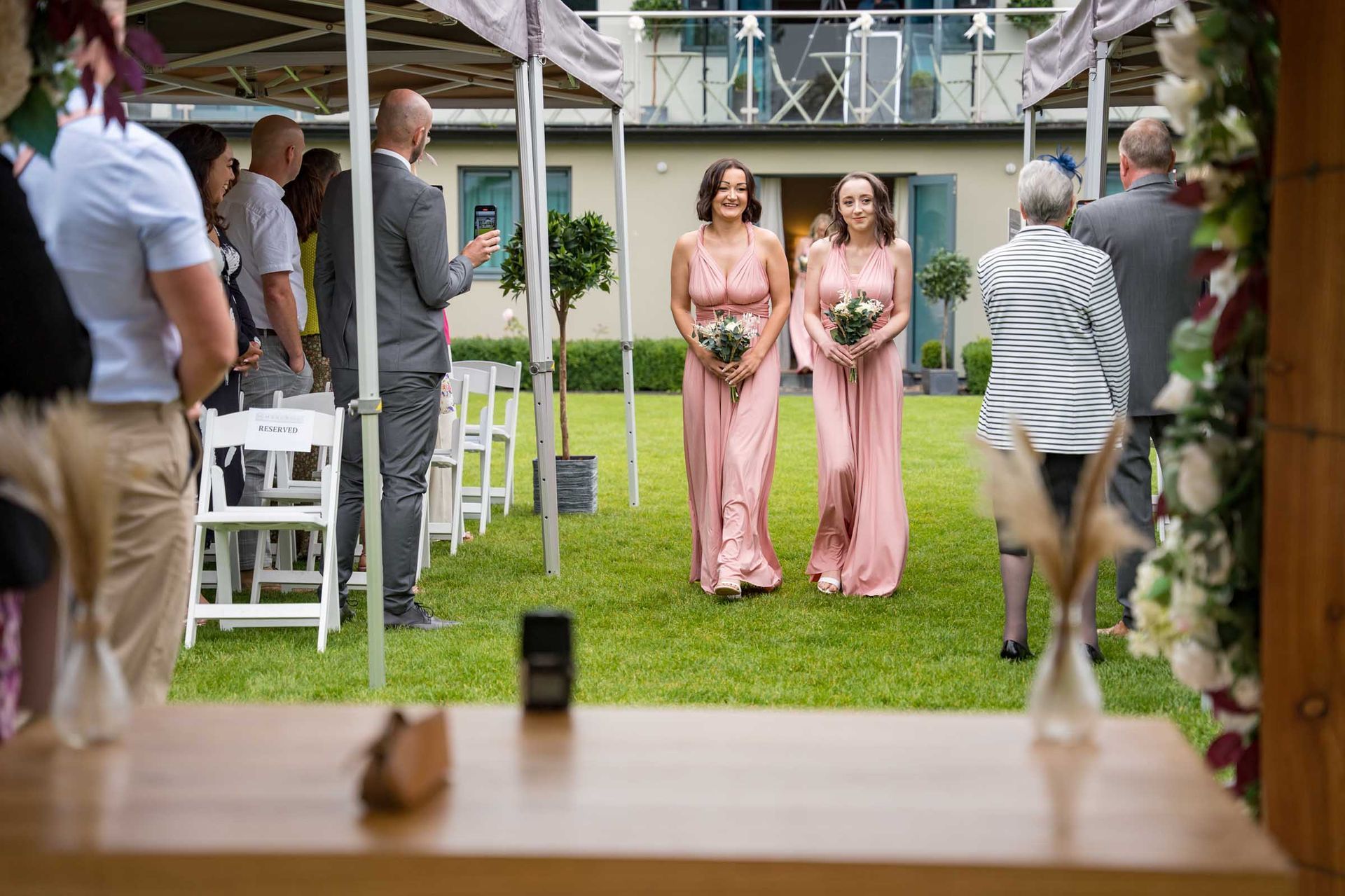 A bride and her bridesmaids are walking down the aisle at a wedding.