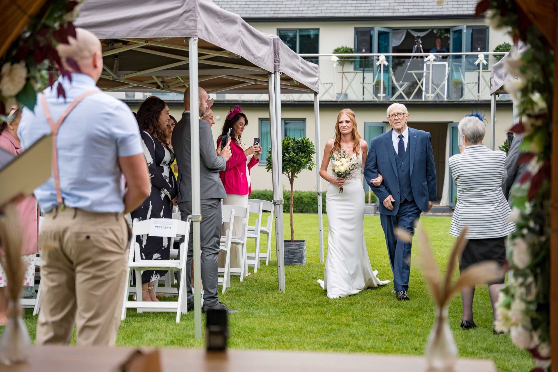 A bride and her father are walking down the aisle at a wedding ceremony.