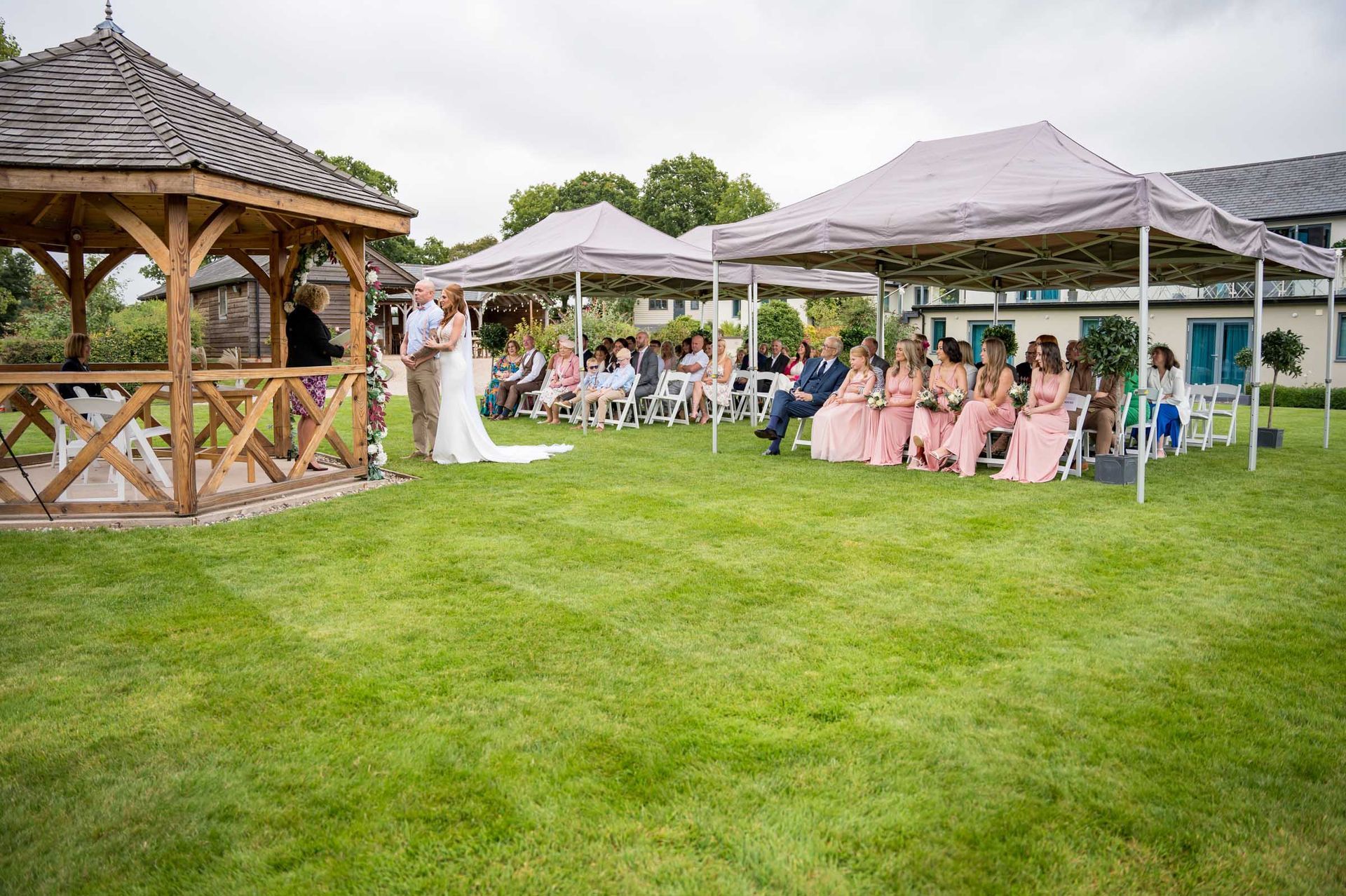 A bride and groom are getting married in front of a gazebo.