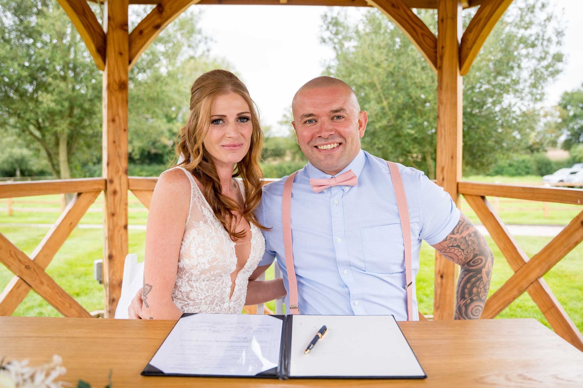 A bride and groom are posing for a picture under a gazebo.