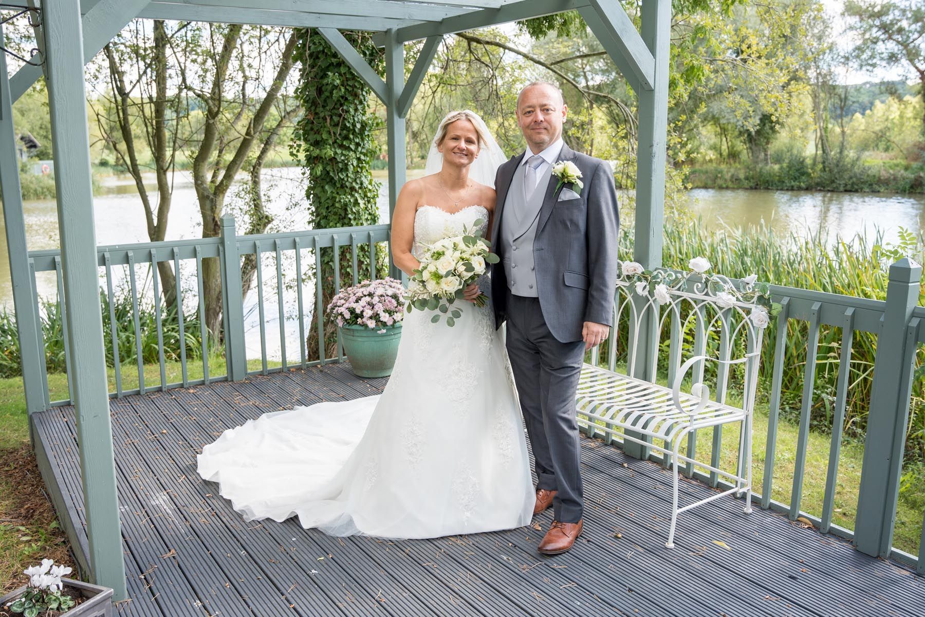 A bride and groom are posing for a picture under a gazebo.
