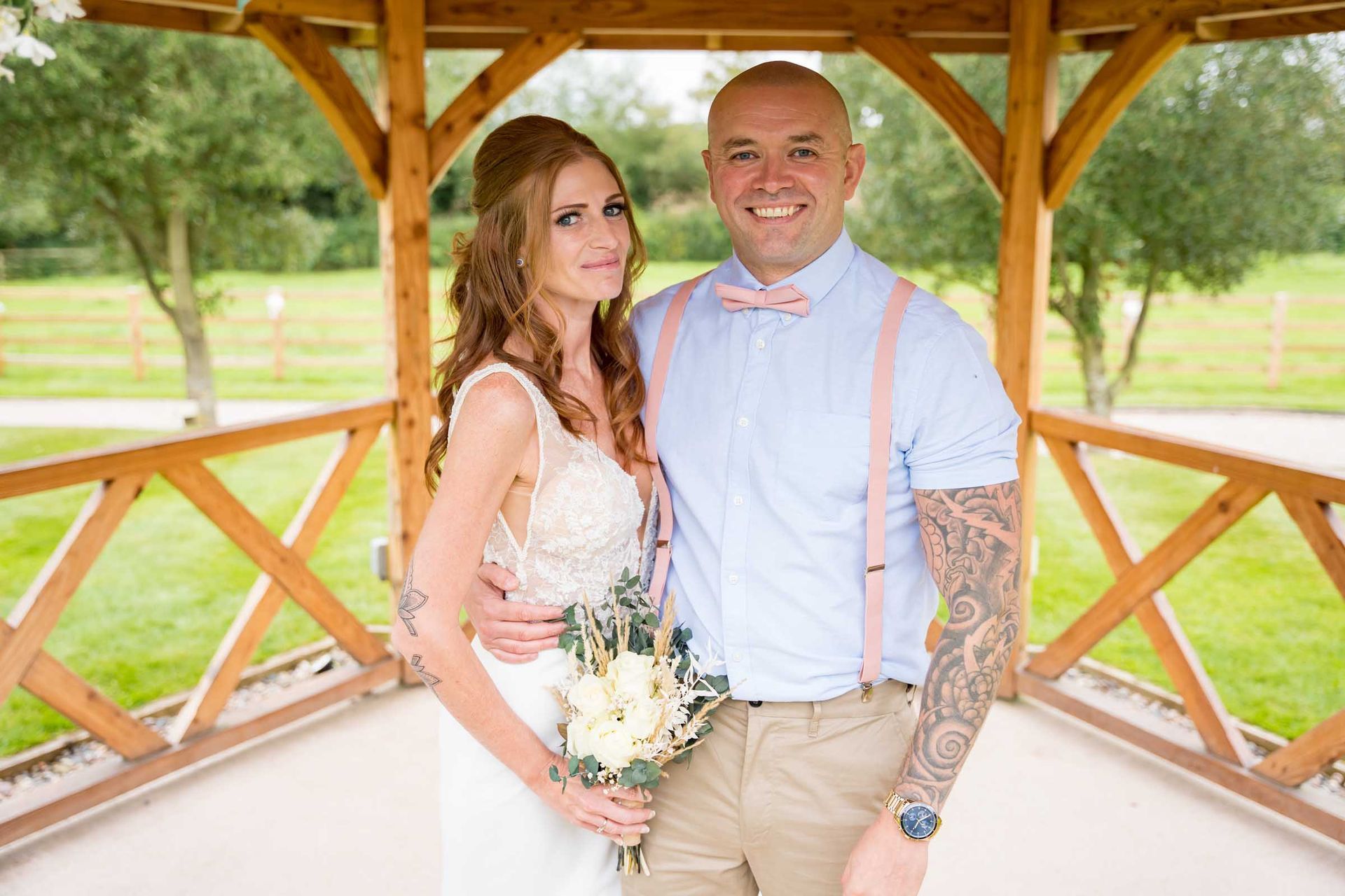 A bride and groom are posing for a picture in front of a gazebo.