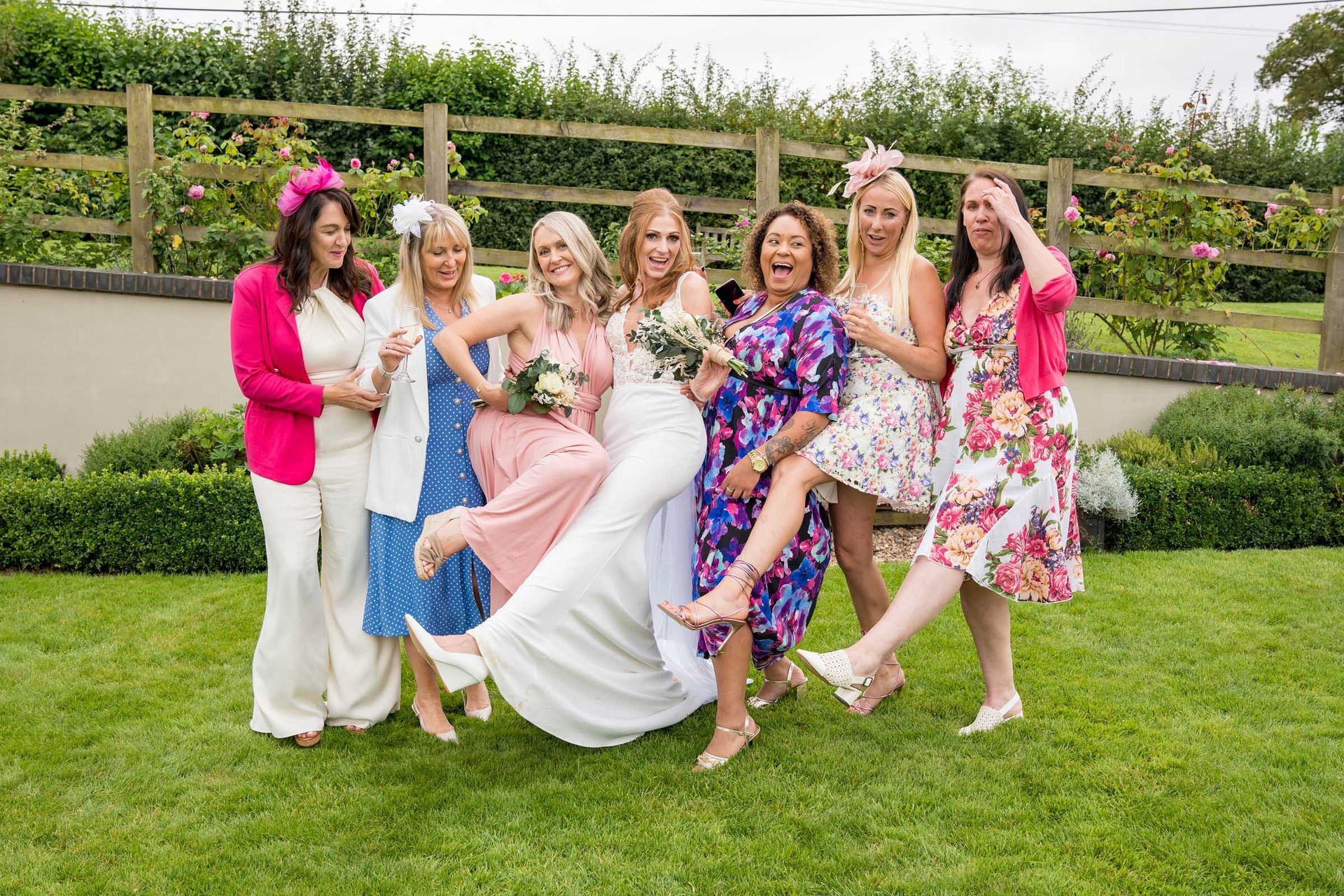A bride and her bridesmaids are posing for a picture in the grass.